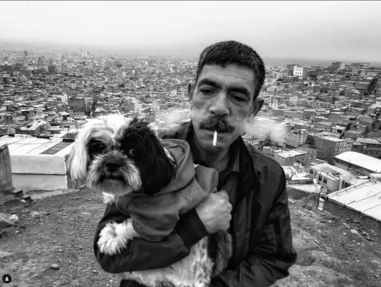1. Uomo con cane su terrazza con città sullo sfondo in bianco e nero.