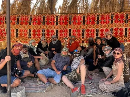 Gruppo di amici in un deserto con tende colorate, viaggio avventura in stile safari, ricordo di un'esperienza di viaggio unica.