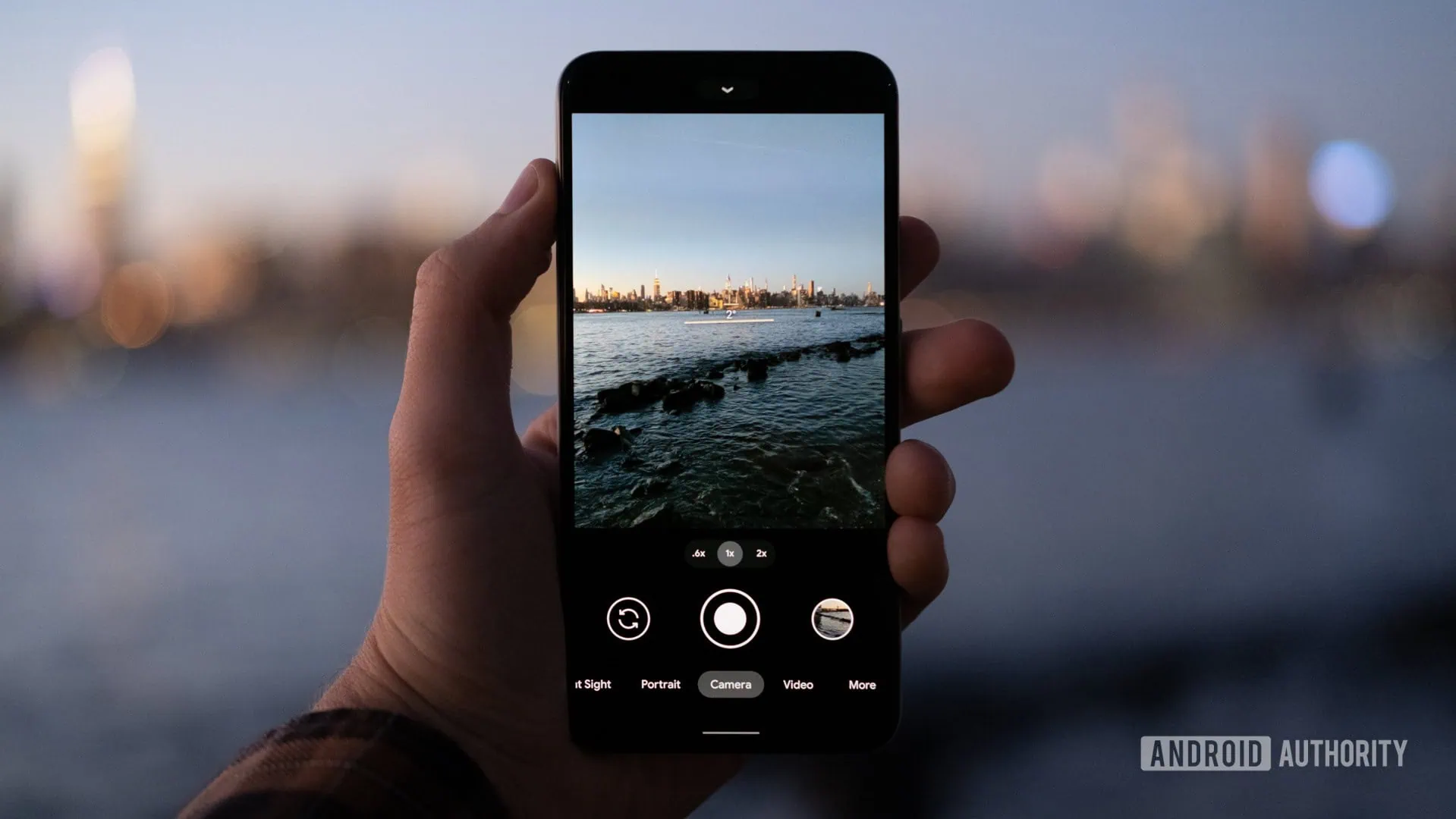 Scatto fotografico di una città sul lungomare al tramonto con smartphone.