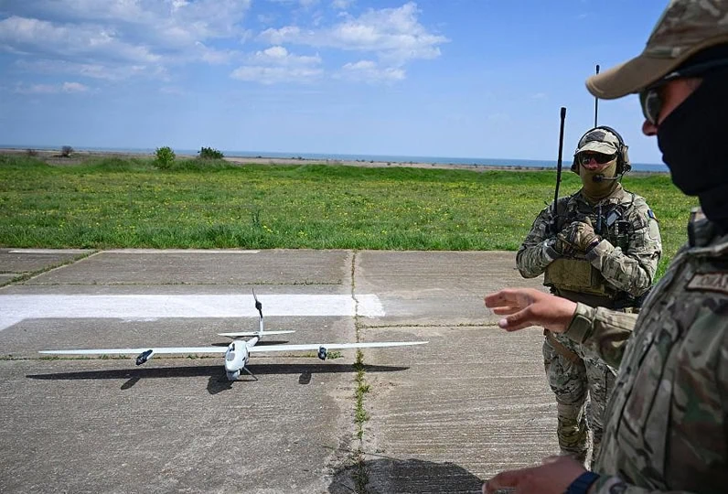 Volo drone militare in campo aperto con operatori in uniforme.