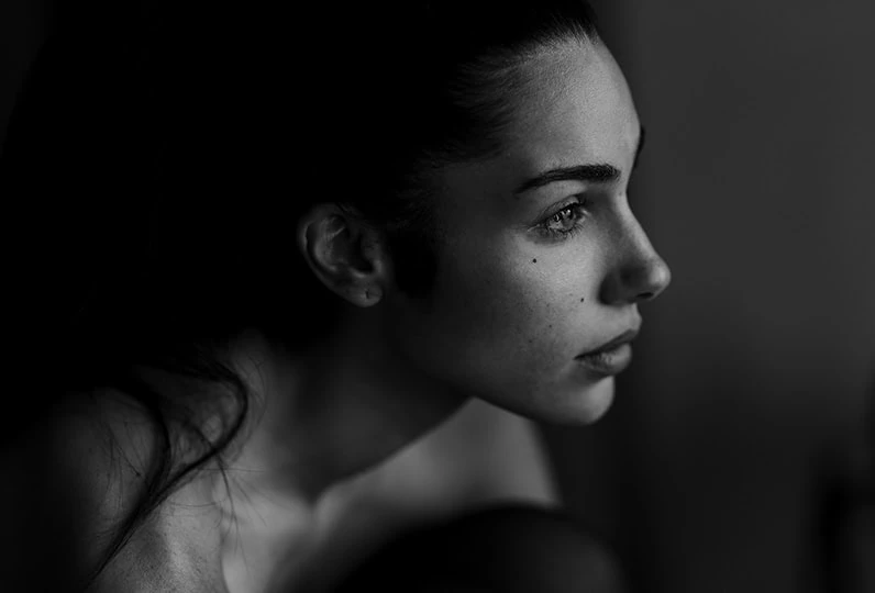 Ragazza in primo piano, ritratto in bianco e nero, con espressione pensierosa e sguardo intenso.
